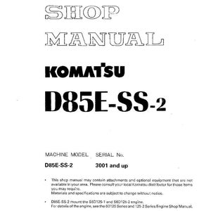 May include: A white shop manual for a Komatsu D85E-SS-2 machine. The cover features the title "SHOP MANUAL" in a bold, outlined font, along with the Komatsu logo and model information. The manual includes technical specifications.