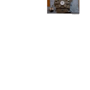 May include: A detailed image of a mechanical component, featuring a complex arrangement of metal parts, screws, and circular elements. The text instructs to disassemble plugs with an L-wrench. The component rests on a blue cloth.