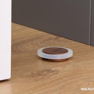 May include: A walnut bottle stopper with a clear, rounded edge. The stopper is 0.63 inches in diameter and sits on a wooden surface. The text "WALNUT - 16mm &asymp; 0.63" is visible at the bottom of the image.
