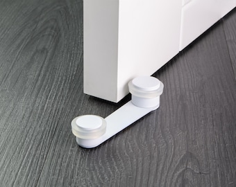 May include: White door stop with two round rubber pads. The door stop is attached to a white door.