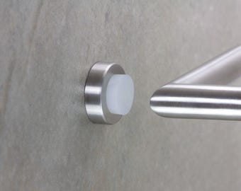 May include: A close-up of a stainless steel door handle and a door bumper. The door bumper is a circular, brushed metal piece with a white, cylindrical buffer. The handle is a curved, brushed metal bar.