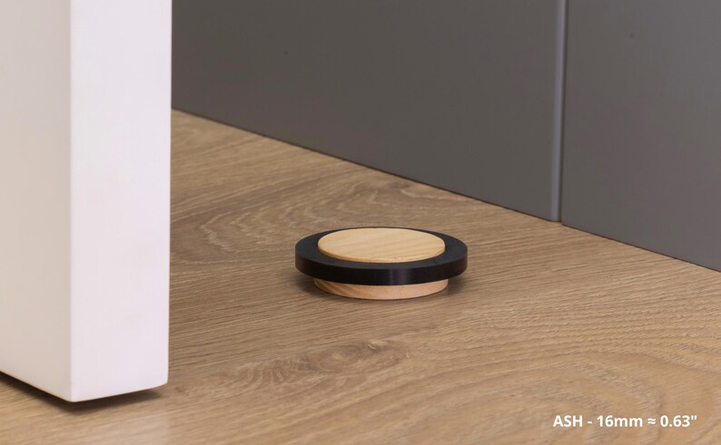 May include: A round, wooden bottle stopper with a black ring and a light wood center. The stopper is approximately 0.63 inches in diameter. The product is labeled "ASH - 16mm &asymp; 0.63".
