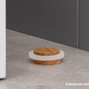 May include: A wooden bottle stopper with a light-colored, circular top and a white, translucent ring. The stopper is made of European oak and is approximately 0.87 inches in diameter. The image is set against a neutral background.