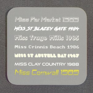 May include: A gray background with white text listing the winners of the Miss Par Market beauty pageant from 1983 to 1989. The text includes the year and the name of the winner, such as "Miss St Blazey Gate 1984" and "Miss Cornwall 1989".