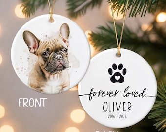 May include: A round white ceramic ornament featuring a watercolor illustration of a fawn French Bulldog on the front. The back displays a black paw print with a heart, the text "forever loved OLIVER" and the years "2016 - 2026" in black ink.