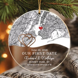 May include: A round, clear acrylic ornament featuring a black and white street map of New York City with a small red heart. Below the map, the text reads: June 22, 2026, OUR FIRST DATE, Richard & Natalya, SUNSET PARK, NY, 40°39'01.8"N 74°01'25.5"W.