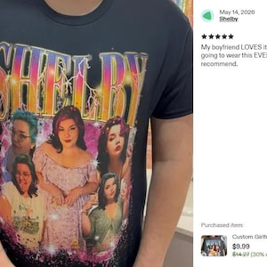 May include: A black short-sleeved t-shirt featuring a graphic print with the word SHELBY in large, multi-colored, lightning-effect letters at the top. Below the text are five distinct photographic portraits of the same person in various poses.
