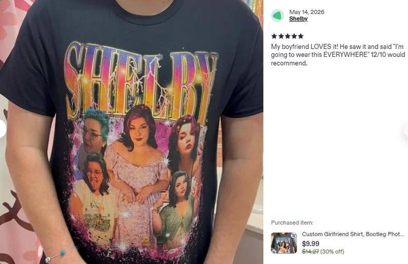 May include: A black short-sleeved t-shirt featuring a graphic print with the word SHELBY in large, multi-colored, lightning-effect letters at the top. Below the text are five distinct photographic portraits of the same person in various poses.