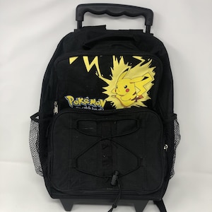 May include: Black rolling backpack featuring a yellow Pikachu graphic with lightning bolts. The backpack has a black handle, wheels, and side mesh pockets. The word "Pokemon" is printed on the front.