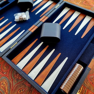 May include: A blue leather backgammon set with white and brown playing pieces. The set is open and ready to play.
