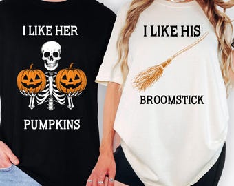 May include: Black and ivory Halloween t-shirts. The black shirt features a skeleton holding two orange pumpkins with the text "I LIKE HER PUMPKINS". The ivory shirt has a broom graphic and the text "I LIKE HIS BROOMSTICK".