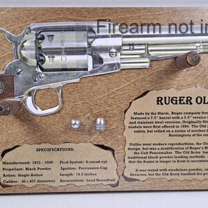 May include: A wooden plaque featuring a detailed illustration of a Ruger Old Army revolver. The silver-colored firearm is mounted on a brown background with text that reads "Firearm not included." The gun's length is 14.3 inches.