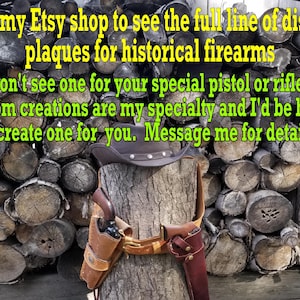 May include: A brown leather holster with a pistol and a matching holster for a rifle are displayed on a tree stump. A cowboy hat sits atop the stump, with text in the background.