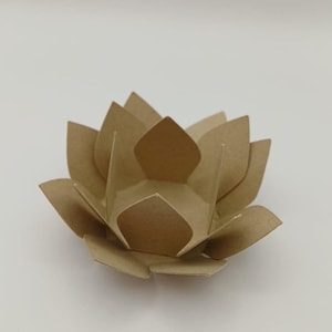 May include: A brown cardboard lotus flower, with multiple layers of folded petals. The flower's petals are pointed and arranged in a circular pattern, creating a three-dimensional effect. The centre of the flower has an opening.
