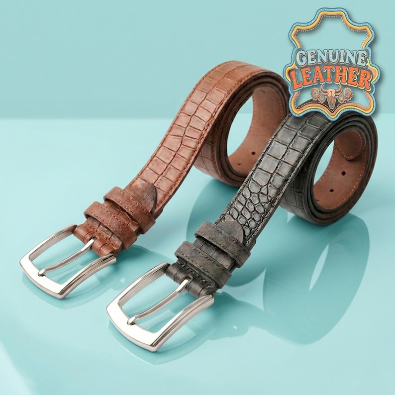 Pu&ograve; includere: Due cinture in pelle con fibbie argentate. Una &egrave; marrone, l'altra grigia. Entrambe le cinture hanno una trama a pelle di coccodrillo. L'immagine include anche un logo "GENUINE LEATHER".