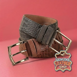 Könnte beinhalten: Drei Ledergürtel in Braun- und Grautönen mit silberfarbenen Schnallen. Die Gürtel haben strukturierte Muster, darunter ein krokodilartiges Design. Ein Etikett mit der Aufschrift "GENUINE LEATHER" ist sichtbar.