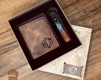 May include: A brown leather wallet with the initials "HCM" embossed on the front, a matching brown leather keychain with a metal tag that also has the initials "HCM" on it, and a small brown leather box with a map pattern.
