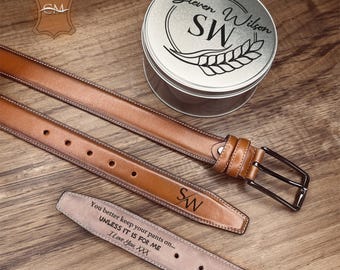 May include: A collection of brown leather belts with silver buckles and personalized initials. A silver tin with the name "Steven Wilson" and initials "SW" is also present. One belt has the text "You better keep your pants on... UNLESS IT IS FOR ME I Love You, XXX."