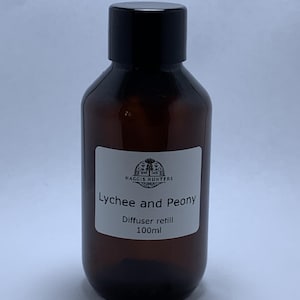 May include: A brown glass bottle with a black lid, labelled "Lychee and Peony Diffuser refill 100ml". The label also features a small logo with the text "HAGGIS HUNTERS".