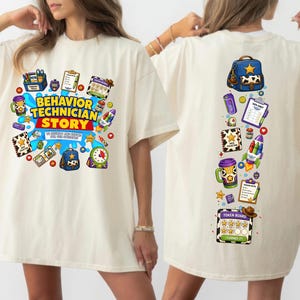 May include: An off-white t-shirt featuring a colorful graphic print. The front displays the text "BEHAVIOR TECHNICIAN STORY" surrounded by illustrations of a backpack, clipboard, rocket, and token board. The back shows a vertical arrangement of these items.