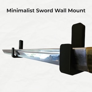 May include: A minimalist black sword wall mount. The mount is designed to hold a sword horizontally against a wall. The sword has a shiny, reflective blade and a brass-coloured hilt. The text "Minimalist Sword Wall Mount" is at the top.