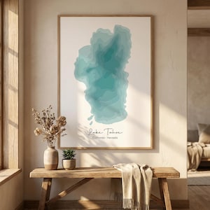 Puede incluir: Una impresión enmarcada del lago Tahoe, California-Nevada, con un diseño topográfico en azul y turquesa. La obra de arte se exhibe en una pared sobre un banco de madera. El texto "Lake Tahoe" y "California - Nevada" está escrito en una fuente de guion.