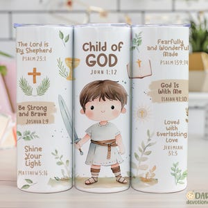 May include: A white tumbler with a watercolour illustration of a child holding a sword, with the text "Child of GOD" and Bible verses. The design includes a cross, chalice, and open book, with floral accents.