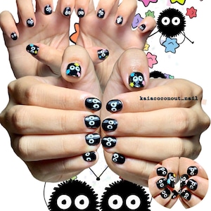 May include: Black nail art featuring cartoon-style characters with white eyes. Some nails have colorful star accents. The image includes the text "kaiacoconut_nail" and a cartoon character.