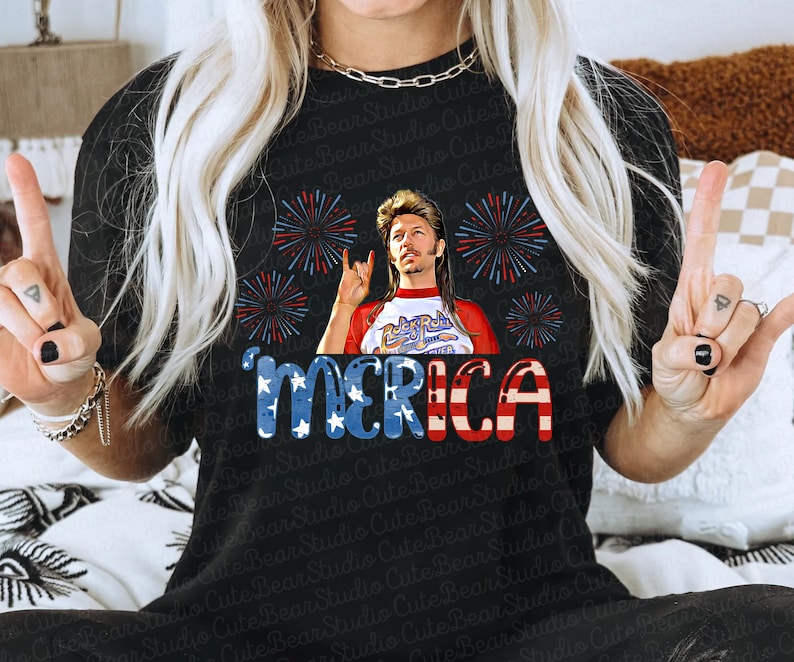 May include: Black t-shirt featuring a red, white and blue American flag design. The flag has the word "MERICA" written on it. A man with a bandana and a backwards baseball cap is in the centre of the flag. He is wearing a red, white and blue shirt with the words "Rock Roll" on it. There are fireworks around the flag.