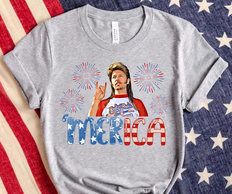 May include: Grey t-shirt featuring a graphic of a man with long blonde hair and a beard wearing a red, white and blue shirt with the words "Rock N Roll" on it. The graphic is surrounded by red, white and blue fireworks. The text "'MERICA" is below the graphic in red, white and blue.