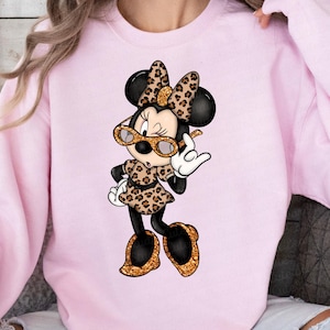 Może przedstawiać: R&oacute;żowa bluza z nadrukiem kresk&oacute;wkowej postaci Minnie Mouse w ubraniach w panterkę i okularach przeciwsłonecznych.