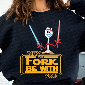 May include: Black sweatshirt with a yellow graphic of a toy character holding lightsabers. The graphic says "May the Fork Be With You".