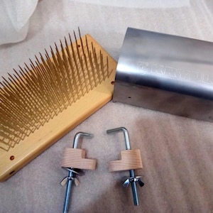 May include: A wooden fiber carding tool with numerous metal pins, a stainless steel rectangular component, and two clamp assemblies. The carding tool is light brown, and the metal components are silver.