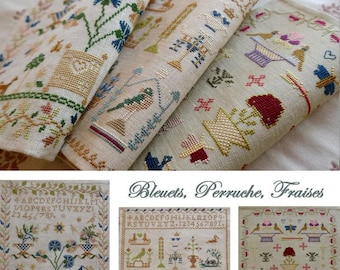 May include: Close-up of several folded, embroidered linen pieces featuring floral and bird designs in various colors. The designs include blue, green, red, and gold thread. The text "Bleuets, Perruche, Fraises" is visible.
