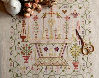 May include: A detailed cross-stitch sampler featuring a central altar design with the letters "IHS" and the text "maria s ad 1864". The sampler includes floral and vine motifs in shades of pink, green, and gold, with a pair of gold scissors.