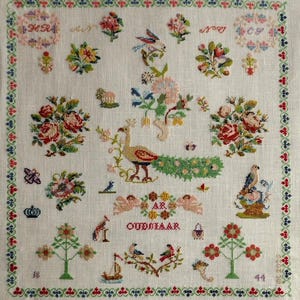 Può includere: Un dettagliato ricamo a punto croce su tessuto bianco, con motivi floreali e di uccelli. Il disegno include un pavone, rose e il testo "OUDDIJAAR". Il bordo è un motivo ripetitivo rosso, verde e blu. I numeri 18 e 44 sono visibili.