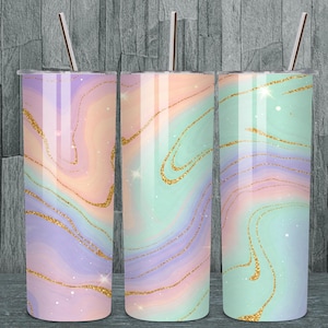 Puede incluir: Tres vasos de acero inoxidable con tapas y pajitas. Cada vaso presenta un diseño pastel en espiral en tonos de morado, melocotón y verde menta, acentuado con líneas doradas brillantes. Los vasos están diseñados para bebidas frías.