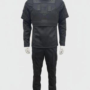 May include: A black tactical uniform displayed on a mannequin. The outfit includes a long-sleeved shirt with a high collar, a chest plate, and cargo pants. The uniform is designed with multiple pockets and reinforced panels.