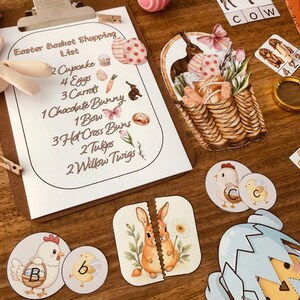 May include: An Easter-themed collection featuring a shopping list, a basket with eggs and flowers, and various decorative elements. The shopping list includes items like cupcakes, eggs, carrots, and a chocolate bunny. Other elements include a puzzle of a bunny and chick-themed circles.