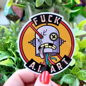 Puede incluir: Una pegatina redonda con un dise&ntilde;o de robot. El robot tiene la cabeza agrietada, una lengua fuera y cables coloridos. La pegatina tiene el texto "FUCK A.I. ART" en un c&iacute;rculo rojo con una l&iacute;nea que lo cruza.