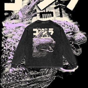 Può includere: Maglietta nera a maniche lunghe con un aspetto usurato. La maglietta presenta una stampa grafica di un mostro con la parola giapponese "ゴジラ" (Godzilla) stampata sopra.