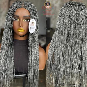 May include: A gray and white braided wig on a mannequin head. The wig features long, individual braids with a natural-looking part. The mannequin is wearing a black top and has a tag attached. The wig is styled to fall down the back.