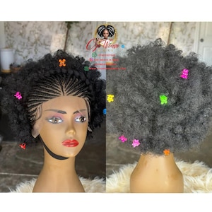 Puede incluir: Peluca negra con frente trenzado y espalda rizada y voluminosa, adornada con horquillas en forma de estrella de colores. La peluca se exhibe en una cabeza de maniquí con un rostro realista y lápiz labial rojo.