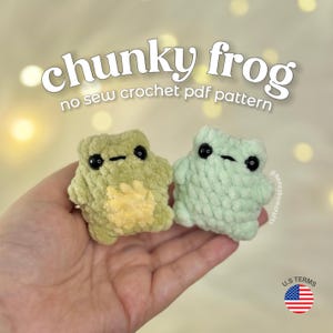 Puede incluir: Dos ranas de ganchillo hechas a mano en tonos verdes y verde claro. Las ranas tienen ojos negros y están etiquetadas como "chunky frog" y "no sew crochet pdf pattern". Las ranas se sostienen en una mano.