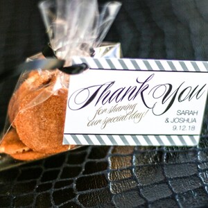 May include: A small clear bag with a thank you tag attached. The tag is white with black stripes and says "Thank You for sharing our special day!" with the names Sarah & Joshua and the date 9.12.18. The bag contains two small round cookies.