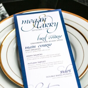 Puede incluir: Una tarjeta de menú de boda azul y blanca con ribete dorado. El menú enumera los platos de la recepción de la boda: primer plato, plato principal, acompañamientos y postre. La tarjeta dice "Megan & Harry" y "Septiembre 7, 2017".