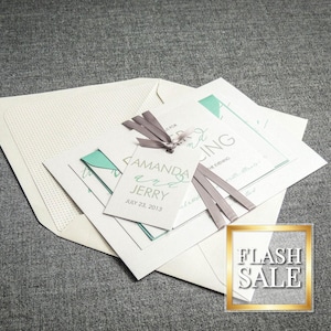 May include: Wedding invitation suite with a teal and white color scheme. The invitation features the text "Amanda and Jerry" with the date "July 23, 2013". The RSVP card features the text "RSVP" and the text "with love, Amanda and Jerry".