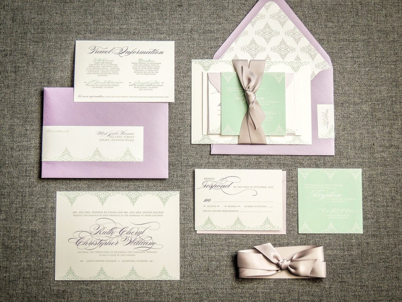 May include: Wedding invitation suite with a green and purple color scheme. The invitation features a delicate floral design and the names "Ruth Cheryl" and "Christopher William". The RSVP card includes a response line and a space for guests to write their names.