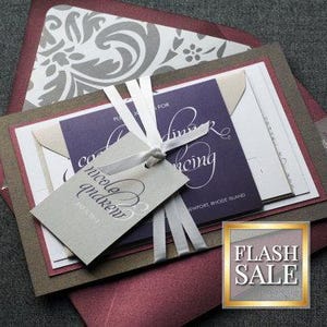 May include: A wedding invitation suite with a burgundy, gray, and purple color scheme. The invitation features a damask pattern and the text "Nicole and Andrew" and "Wedding" in a cursive font.