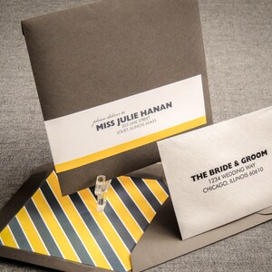 May include: A brown envelope with a yellow and black striped envelope flap. The envelope has a white label with the text "please deliver to Miss Julie Hanan, 203 Lime Street, Jouet, Illinois 60435". A smaller white envelope with the text "The Bride & Groom, 1234 Wedding Way, Chicago, Illinois 60610" is on top of the envelope.